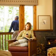 Woman reading and enjoying a glass of wine in a guestroom at the Kenai Princess Lodge